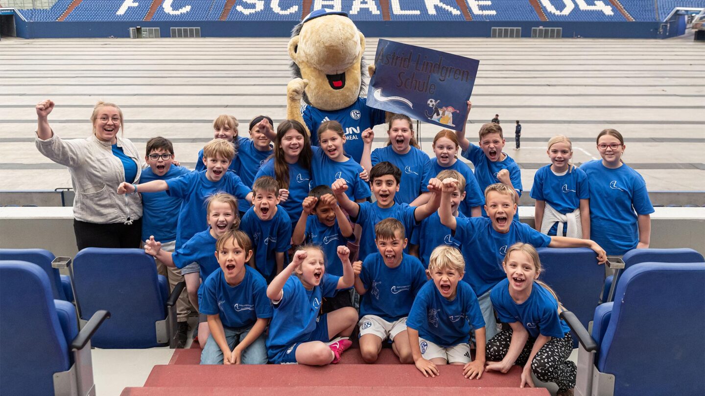 Eine Schulklasse macht ein ausgelassenes Gruppenfoto mit ERWIN.