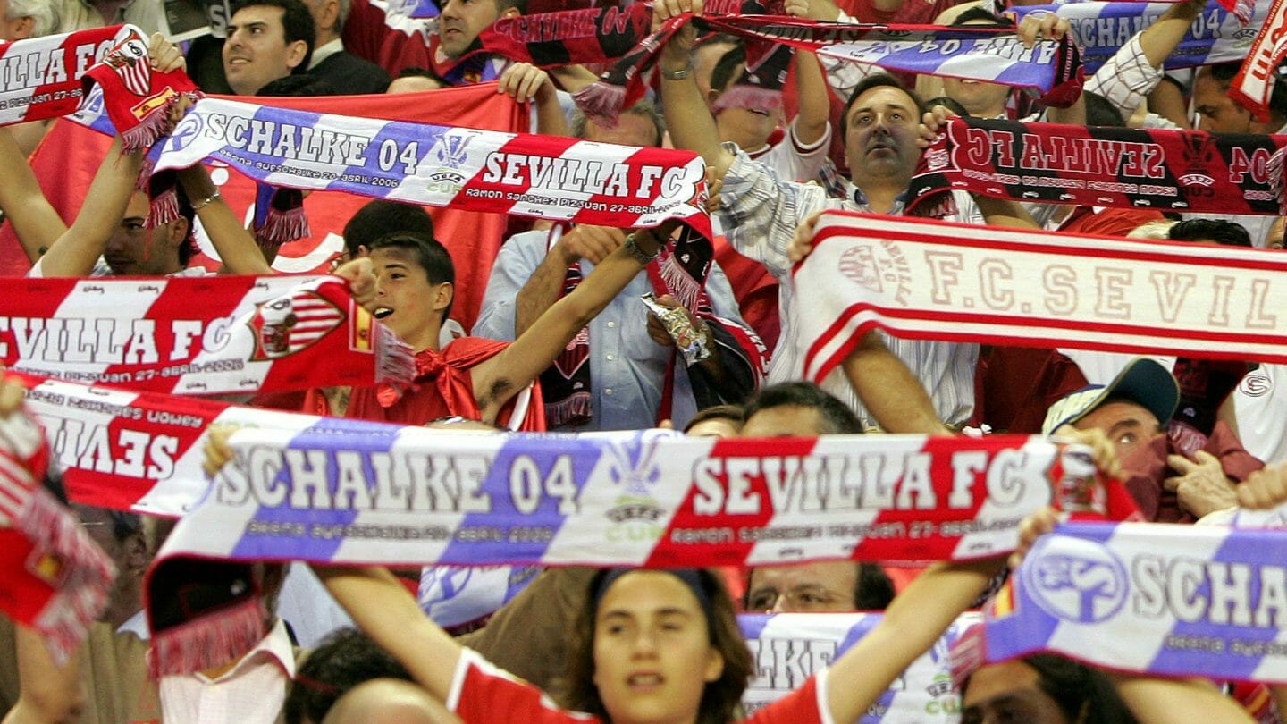 Fans holding up half-and-half Schalke and Sevilla scarves.