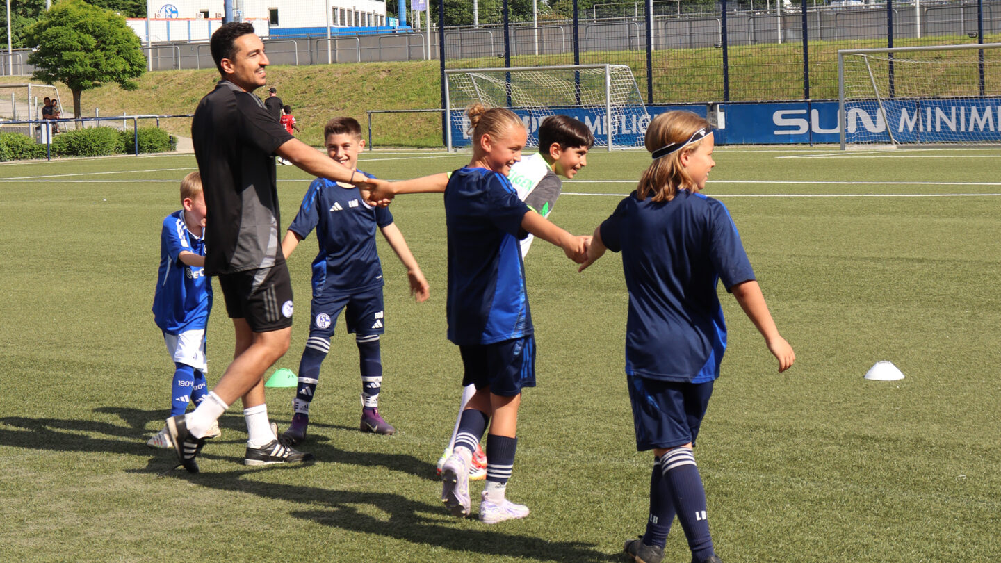 Trainer und Kinder bei einer Übung auf dem Platz