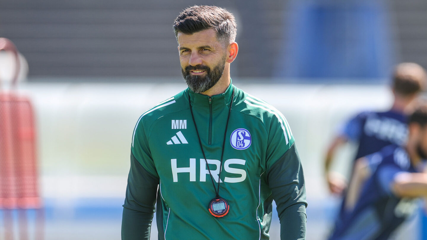 Miron Muslic läuft in Teamwear über den Trainingsplatz und trägt dabei eine Stoppuhr um den Hals.