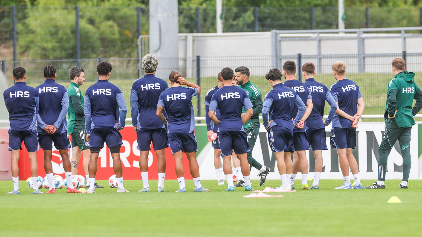 Chef-Trainer Miron Muslic steht inmitten der Trainingsgruppe auf dem Platz und erklärt etwas.