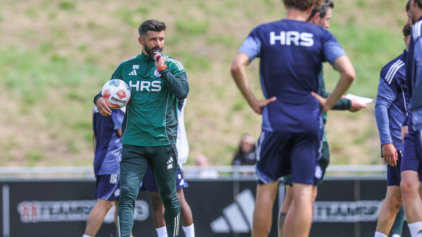 Chef-Trainer Miron Muslic hat einen Ball im Arm und bläst auf dem Trainingsplatz in seine Pfeife.