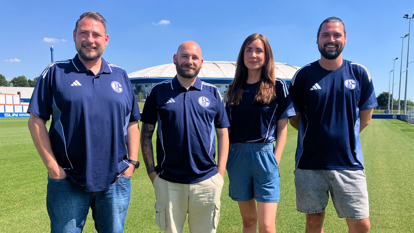 Die Fanbelange-Ansprechpartner Daniel Fehrholz, Sven Graner, Lisa Limberg und Julian Rudnik stehen nebeneinander auf dem Rasen vor der VELTINS-Arena.
