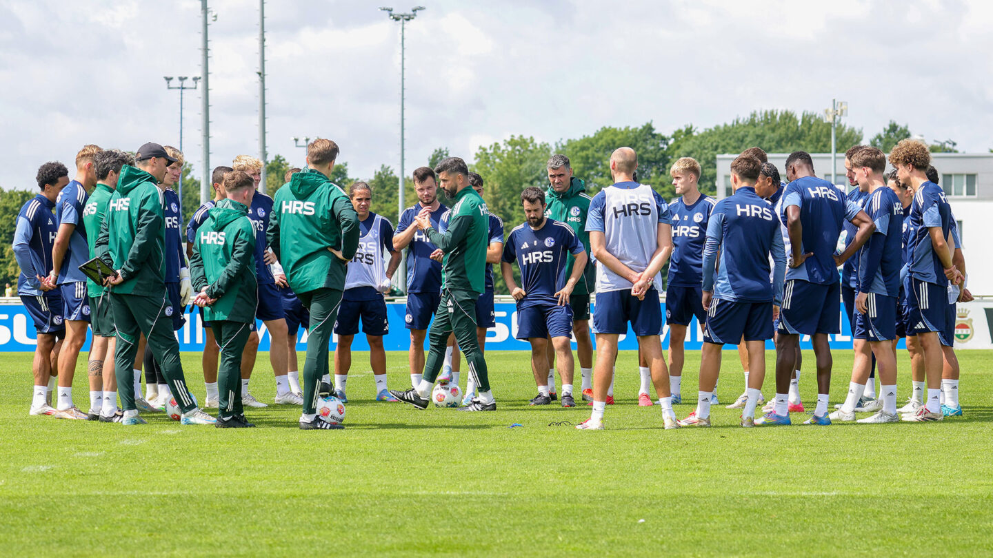 Chef-Trainer Miron Muslic steht auf dem Trainingsplatz inmitten seiner Spieler und gibt Anweisungen.