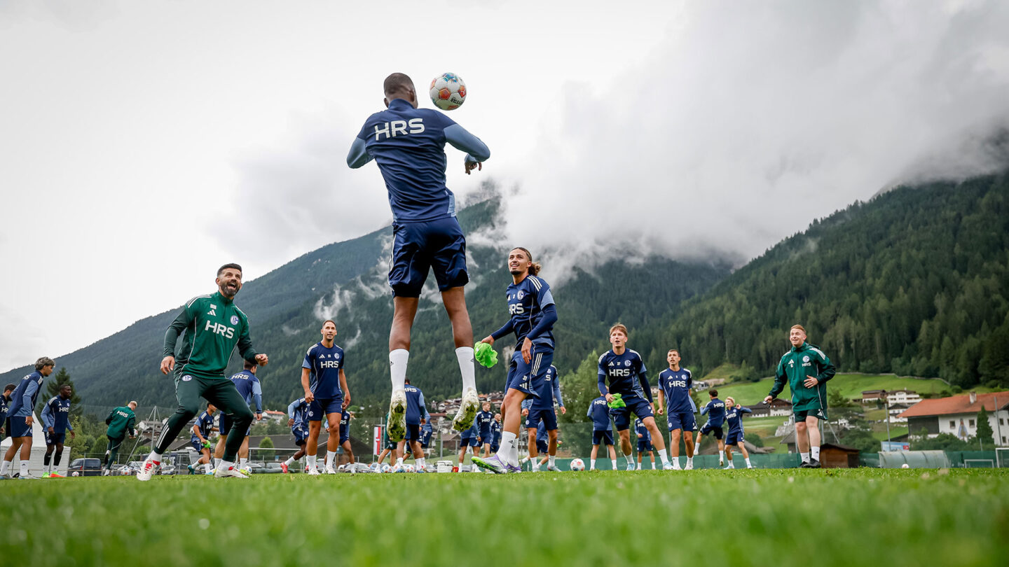 Die Mannschaft beim Kreisspiel im Auftakttraining im Stubaital. Im Hintergrund sind Berge zu sehen.
