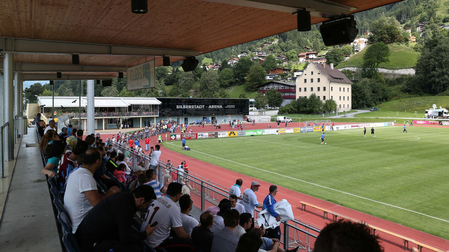 Fans sitzen auf der Haupttribüne der Silberstadt Arena und schauen ein Spiel.