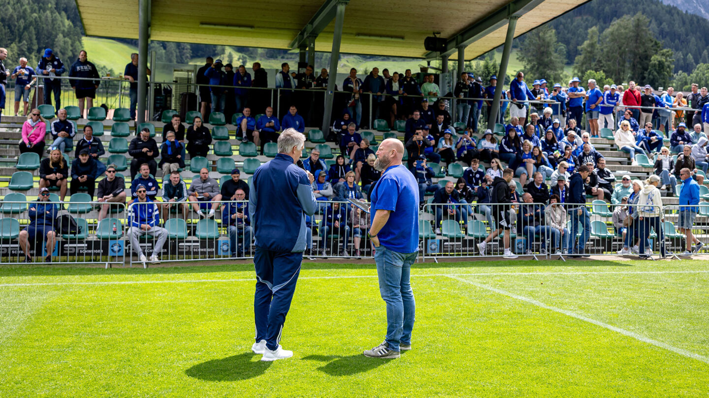 Frank Baumann im Gespräch mit Kai Regnitter. Im Hintergrund ist die Tribüne mit vielen Fans zu sehen.