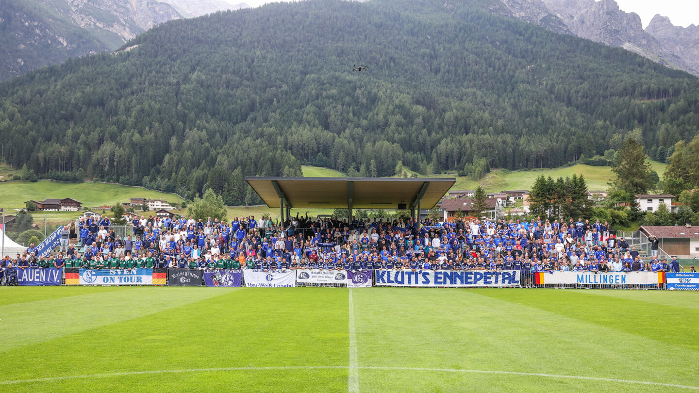Gemeinsames Mannschaftsfoto von Team und Fans auf der Tribüne des FC Stubai. Im Hintergrund sind Berge zu sehen.