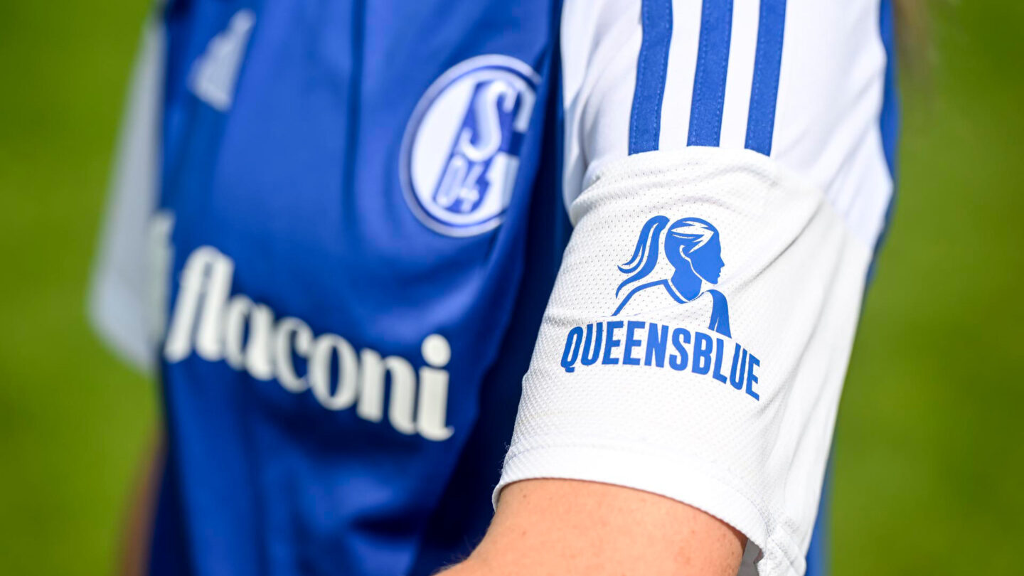 Nahaufnahme eines S04-Frauen-Trikots mit dem Ärmel im Fokus, der das Queensblue-Logo zeigt.