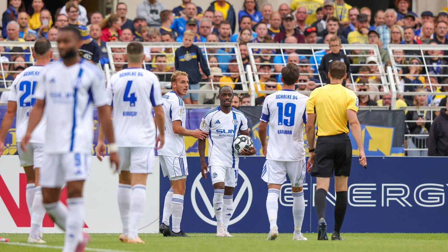 Christopher walks towards the referee with the ball in his hand