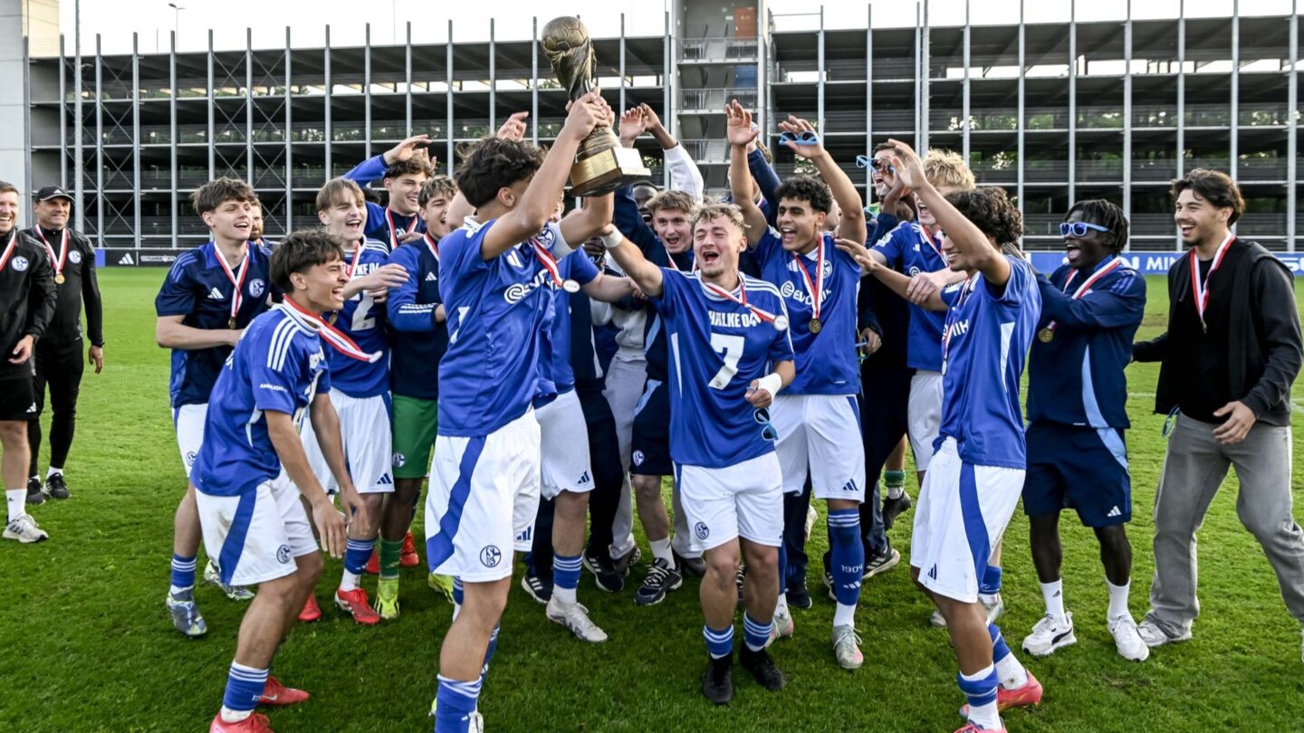 Die Schalker U17-Spieler recken den Westfalenpokal in die Höhe und jubeln gemeinsam im Kreis.
